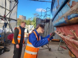 Workers at Cody Dock restoring the hull of a wodden boat